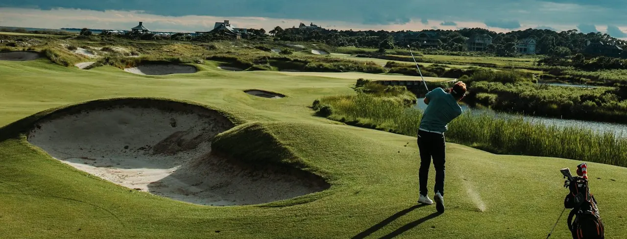 A golfer playing a links course among the dunes